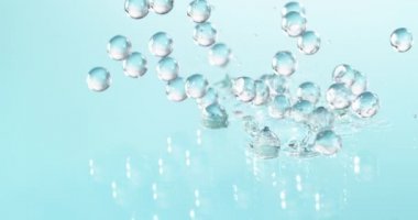 Düşen mavi hidrojel toplarının süper yavaş çekimi. Kozmetik, gençlik ve güzellik konsepti. Yüksek hızlı sinema kamerası, 1000fps