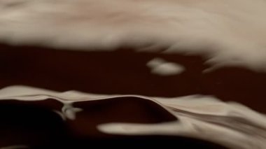 Koyu sıcak çikolatanın çok yavaş sıçratması, yakın çekim. Yüksek hızlı sinema kamerası, 1000fps.