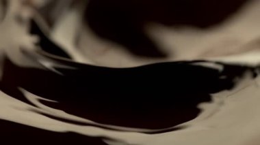 Koyu sıcak çikolatanın çok yavaş sıçratması, yakın çekim. Yüksek hızlı sinema kamerası, 1000fps.