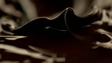 Koyu sıcak çikolatanın çok yavaş sıçratması, yakın çekim. Yüksek hızlı sinema kamerası, 1000fps.