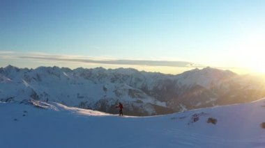 Genç adam Alplerde kayağa tırmanıyor. Kış aktivitesinin hava görüntüleri. Alpin tırmanışı, güzel karlı dağ zirveleri.