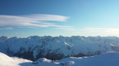 Genç adam Alplerde kayağa tırmanıyor. Kış aktivitesinin hava görüntüleri. Alpin tırmanışı, güzel karlı dağ zirveleri.