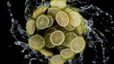 Su sıçratan limon dilimlerinin süper yavaş çekimleri, siyah arkaplan. Yüksek hızlı sinema kamerası, 1000 fps. Hız rampası etkisi.