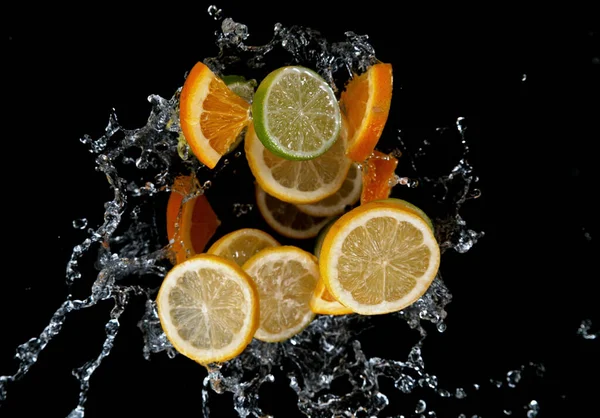 Zamrozić Ruch Pokrojonych Limonek Cytryn Cytryn Rozprysku Wody Izolacja Czarnym — Zdjęcie stockowe