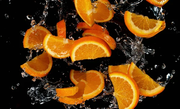 Fagyaszd Meg Felszeletelt Narancs Mozgását Vízfröccsenésben Elkülönítve Fekete Háttér — Stock Fotó