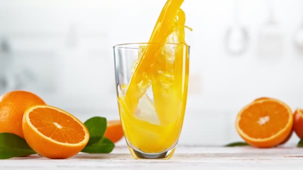 把橙汁倒入玻璃杯的超级慢动作 放在有厨房内部的白色桌子上 用高速摄像机拍摄 每秒1000帧 速度斜坡效应 — 图库视频影像