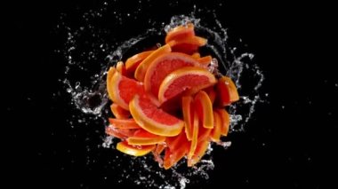 Su sıçratan greyfurt dilimlerinin süper yavaş çekimleri, siyah arkaplan. Yüksek hızlı sinema kamerası, 1000 fps. Hız rampası etkisi.