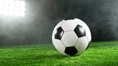 Çimlerin üzerinde dumanlı ve yağmurlu futbol topunun süper yavaş çekimi. Yüksek hızlı sinema kamerası, 1000fps.