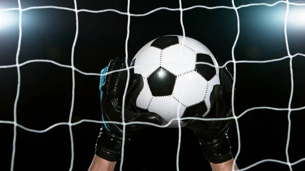 Soccer goalkeeper catching the ball, isolated on black background. Football and soccerr background.