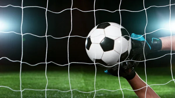 Soccer goalkeeper catching the ball, isolated on black background. Football and soccerr background.