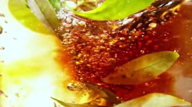 Kasırga şeklinde suya çay dökmek çok yavaş bir hareket. İçeride taze yeşil yapraklar var. Yüksek hızlı sinema kamerası, 1000fps.