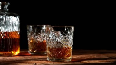 Buz küpünün viski içkisine düşmesi çok yavaş bir hareket. Eski ahşap masaya yerleştirilmiş. Yüksek hızlı sinema kamerası, 1000fps