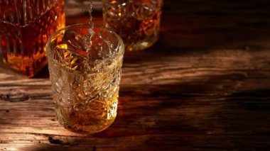 Super slow motion of falling ice cube into whisky drink. Placed on old wooden table. Filmed on high speed cinema camera, 1000fps. Speed ramp effect.