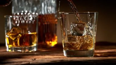 Viskiyi cama dökmenin süper yavaş bir yolu. Eski ahşap masaya yerleştirilmiş. Yüksek hızlı sinema kamerası, 1000fps.