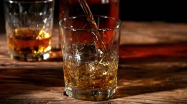 Viskiyi cama dökmenin süper yavaş bir yolu. Eski ahşap masaya yerleştirilmiş. Yüksek hızlı sinema kamerasıyla çekildi, 1000fps. Hız rampası etkisi.