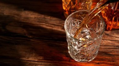 Super slow motion of pouring whiskey into glass. Placed on old wooden table. Filmed on high speed cinema camera, 1000fps.