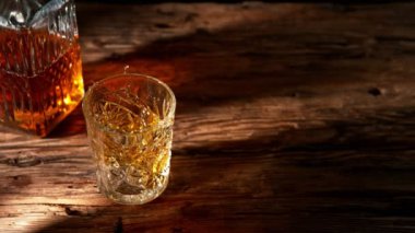 Super slow motion of falling ice cube into whisky drink. Placed on old wooden table. Filmed on high speed cinema camera, 1000fps