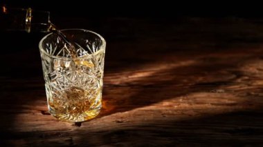Super slow motion of pouring whiskey into glass. Placed on old wooden table. Filmed on high speed cinema camera, 1000fps.