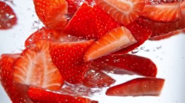 Suyun altında dönen çileklerin süper yavaş çekimi, beyaz arka plan. Yüksek hızlı sinema kamerası, 1000 fps..