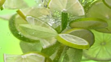 Su altında dönen limon dilimlerinin süper yavaş çekimi, yeşil arka plan. Yüksek hızlı sinema kamerası, 1000 fps. Hız rampası etkisi.