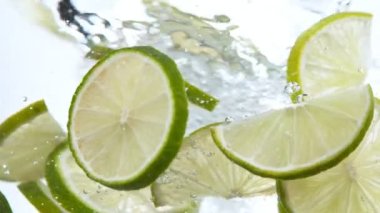 Super slow motion of rotating lime slices underwater, white background. Filmed on high speed cinema camera, 1000 fps.
