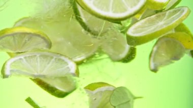 Super slow motion of rotating lime and ice cubes underwater, green background. Filmed on high speed cinema camera, 1000 fps.