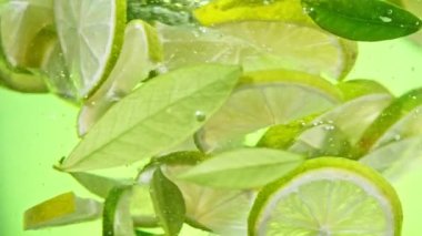 Super slow motion of rotating lime slices underwater, green background. Filmed on high speed cinema camera, 1000 fps.