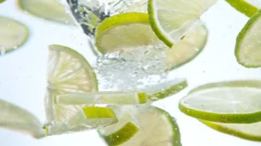 Super slow motion of rotating lime slices underwater, white background. Filmed on high speed cinema camera, 1000 fps.