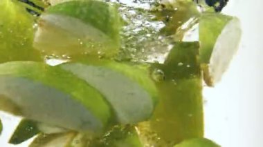 Dilimlenmiş yeşil elma parçalarını suyun altında döndürmek için süper yavaş çekim. Yüksek hızlı sinema kamerası, 1000 fps. Hız rampası etkisi.