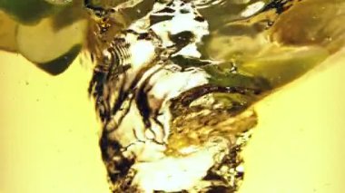 Dilimlenmiş yeşil elma parçalarını suyun altında döndürmek için süper yavaş çekim. Yüksek hızlı sinema kamerası, 1000 fps..