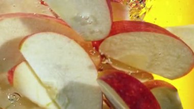 Dilimlenmiş kırmızı elma parçalarını suyun altında döndürmek için süper yavaş çekim. Yüksek hızlı sinema kamerası, 1000 fps. Hız rampası etkisi.