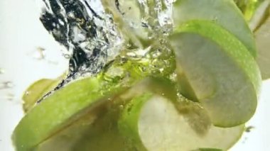Dilimlenmiş yeşil elma parçalarını suyun altında döndürmek için süper yavaş çekim. Yüksek hızlı sinema kamerası, 1000 fps..