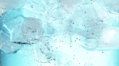 Su altında buz küplerini kapatın, mavi arkaplan. Suda akan buzun dondurucu hareketi.
