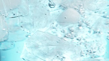 Su altında buz küplerini kapatın, mavi arkaplan. Suda akan buzun dondurucu hareketi.