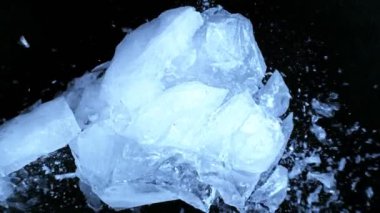 Siyah zemin üzerine düşen buz parçasının süper yavaş çekimi. Yüksek hızlı sinema kamerası, 1000 fps..
