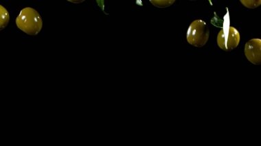 Siyah arka planda düşen yeşil zeytinlerin süper yavaş çekimi. Yüksek hızlı sinema kamerası, 1000fps.