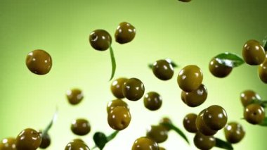Yeşil arka planda uçan yeşil zeytinlerin süper yavaş çekimi. Yüksek hızlı sinema kamerasıyla çekildi, 1000fps. Hız rampası etkisi.