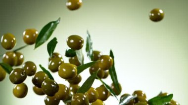 Yeşil arka planda uçan yeşil zeytinlerin süper yavaş çekimi. Yüksek hızlı sinema kamerası, 1000fps.