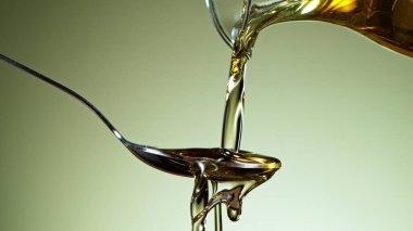 Makro zeytinyağını metal kaşığa dök. Yeşil arkaplanda izole.