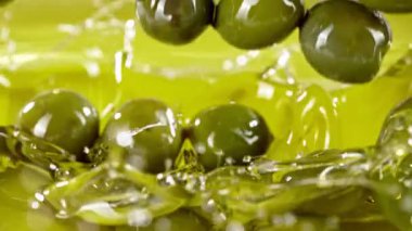 Yeşil zeytinlerin yağın içine düşmesi süper yavaş bir hareket. Yüksek hızlı sinema kamerası, 1000fps.