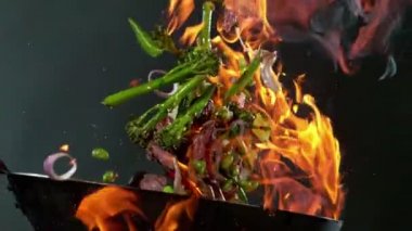 Uçan Asya bifteği ve tavadan sebzeli süper yavaş çekim. Yüksek hızlı sinema kamerası, 1000 fps. Hız rampası etkisi.