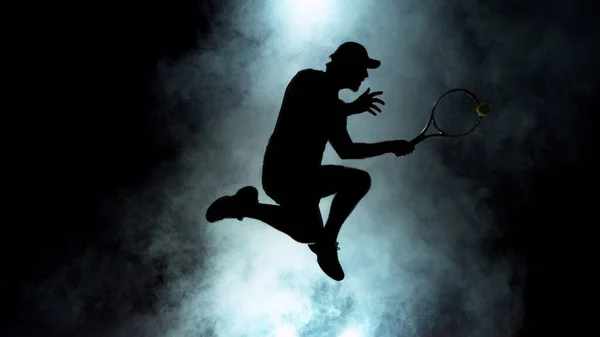 stock image Dramatic tennis player silhouette jumping up in the air. Silhouette with smoke on background, dark wallpaper scene, artistic feeling.