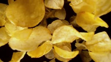 Uçan kızarmış patates cipslerinin süper yavaş çekimi, geniş makro çekim. Siyah arka planda izole edilmiş. Yüksek hızlı sinema kamerası, 1000 fps. Hız rampası etkisi.
