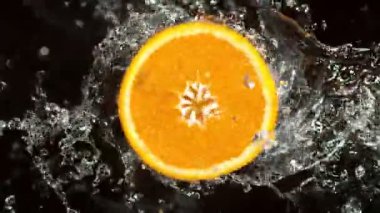 Su Sıçratan Portakal Diliminin Süper Yavaş Hareketi. Dönen Portakal Dilimi ve Sulama Suyu. Kara Arkaplan 'da izole edilmiş. Yüksek Hız Sinema Kamerası, 1000 Fps.