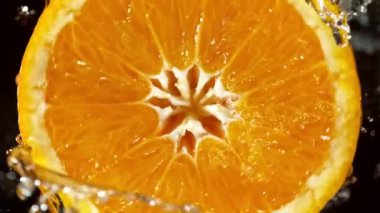 Su Sıçratan Portakal Diliminin Süper Yavaş Hareketi. Dönen Portakal Dilimi ve Sulama Suyu. Kara Arkaplan 'da izole edilmiş. Yüksek Hız Sinema Kamerası, 1000 Fps.