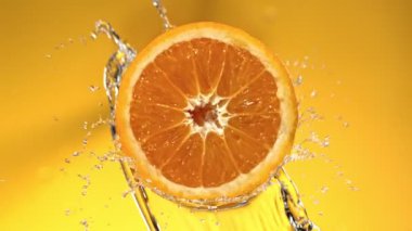Su Sıçratan Portakal Diliminin Süper Yavaş Hareketi. Dönen Portakal Dilimi ve Sulama Suyu. Renkli Arka plan 'da izole edilmiş. Yüksek Hız Sinema Kamerası, 1000 Fps.
