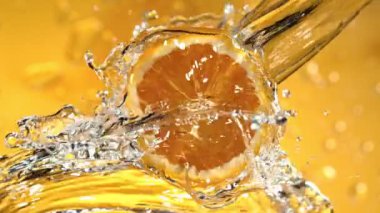 Su Sıçratan Portakal Diliminin Süper Yavaş Hareketi. Dönen Portakal Dilimi ve Sulama Suyu. Renkli Arka plan 'da izole edilmiş. Yüksek Hız Sinema Kamerası, 1000 Fps.