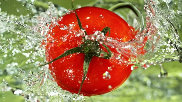 Pomodoro Intero Con Spruzzi Acqua Fondo Verde Isolato Studio Girato — Foto Stock