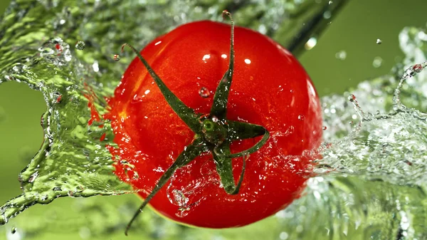 Pomodoro Intero Con Spruzzi Acqua Fondo Verde Isolato Studio Girato — Foto Stock