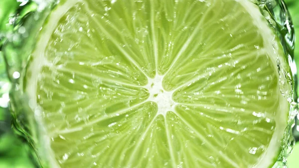 Slice Lime Water Splashes Green Background Isolated Studio Shot Fresh — Stockfoto
